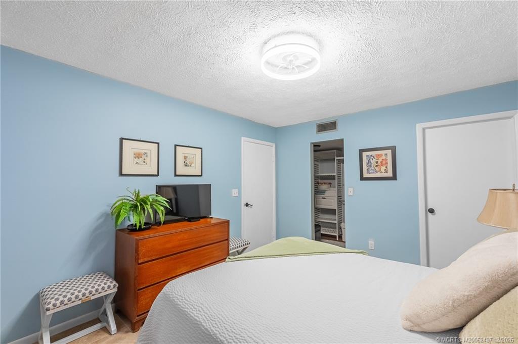 3171 Southeast Aster Lane, Unit 1103 Stuart, FL 34994 - Photo 9 of 26 a bedroom with a bed and a chandelier