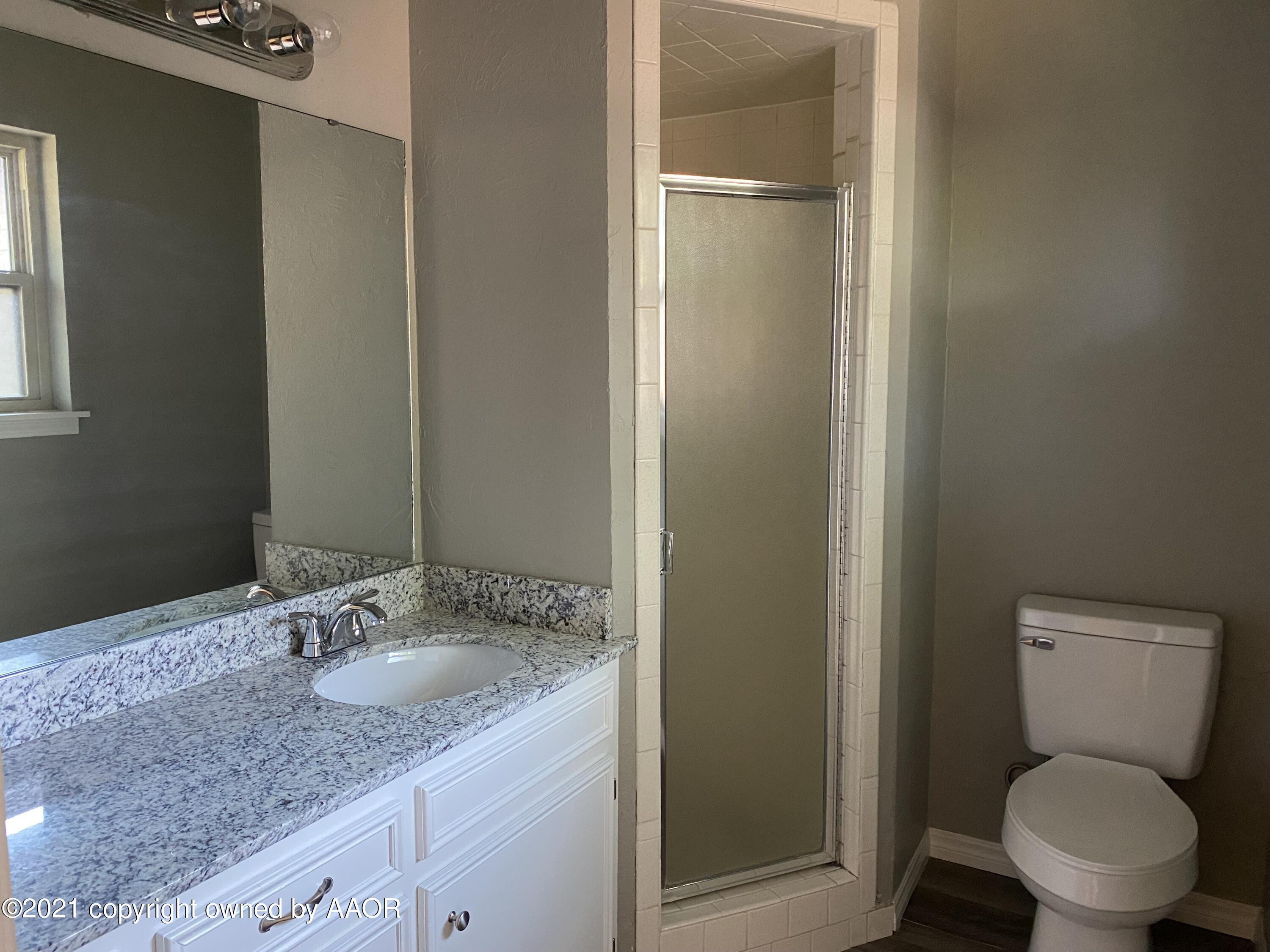 7111 Imperial Trail Amarillo, TX 79106 - Photo 8 of 13 a bathroom with a granite countertop toilet a sink and a mirror