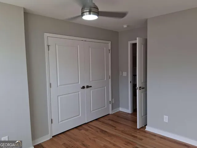 an empty room with wooden floor closet and windows