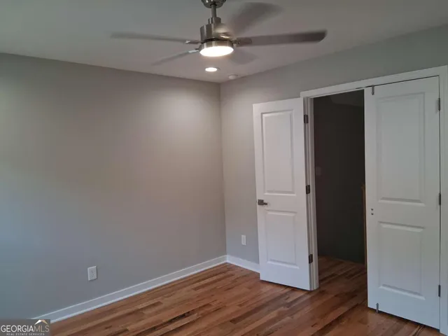 an empty room with wooden floor cabinet and windows