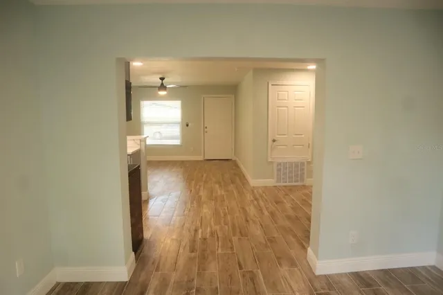 a view of empty room with wooden floor and fan