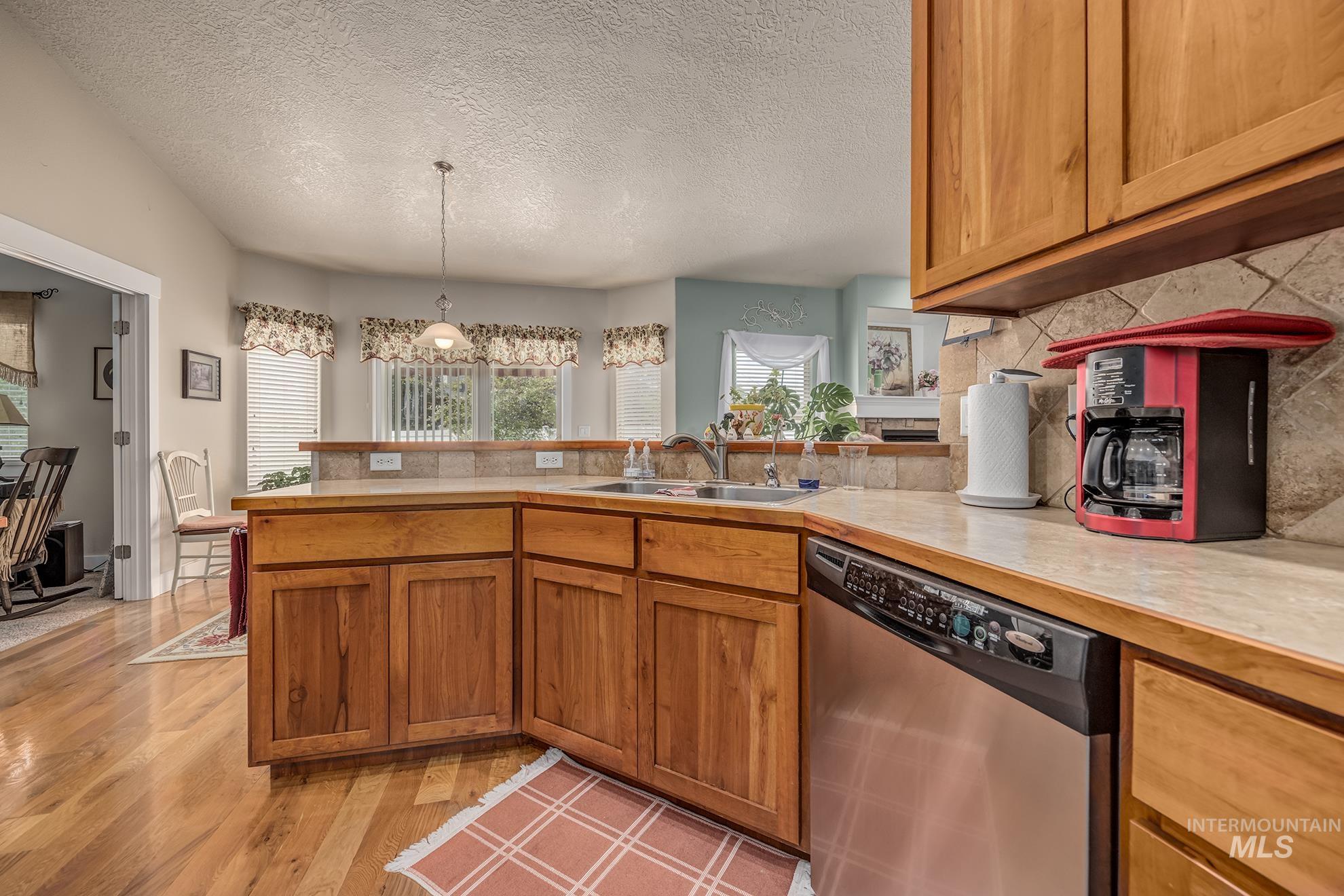 420 West Indianhead Road Weiser, ID 83672 - Photo 15 of 40 Kitchen featuring wood cabinetry, a stainless steel dishwasher, a single basin sink, a tile backsplash, and light countertops