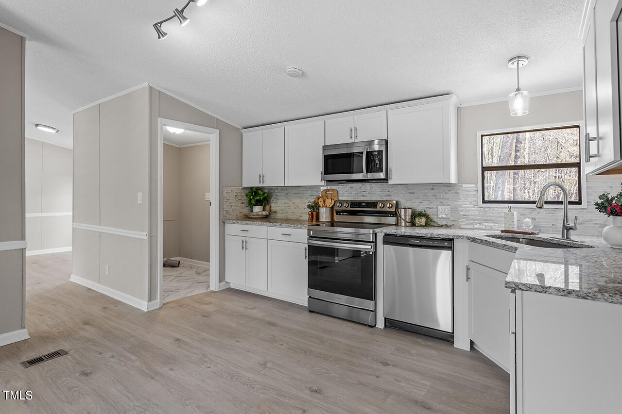 858 Foster Road Henderson, NC 27537 - Photo 11 of 38 a kitchen with granite countertop a refrigerator stove and sink