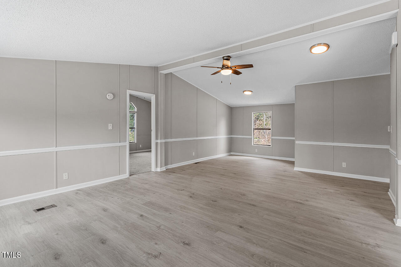 858 Foster Road Henderson, NC 27537 - Photo 16 of 38 a view of empty room with wooden floor and fan