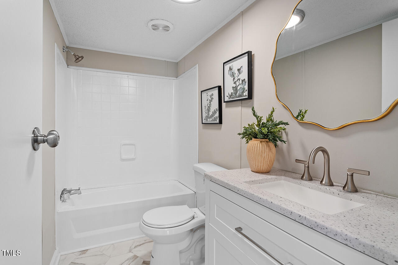 858 Foster Road Henderson, NC 27537 - Photo 8 of 38 a bathroom with a granite countertop sink a toilet and a bathtub