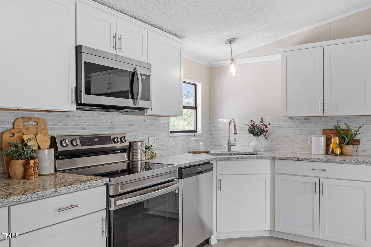 858 Foster Road Henderson, NC 27537 - Photo 9 of 38 a kitchen with granite countertop white cabinets stainless steel appliances and a sink