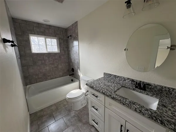 a bathroom with a granite countertop sink a toilet and bathtub