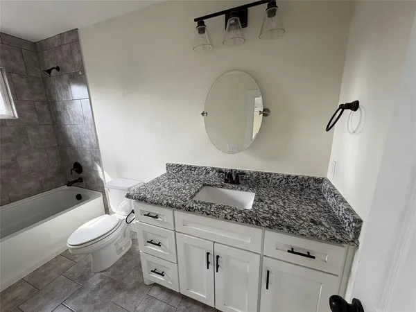 a bathroom with a granite countertop toilet a sink and bathtub
