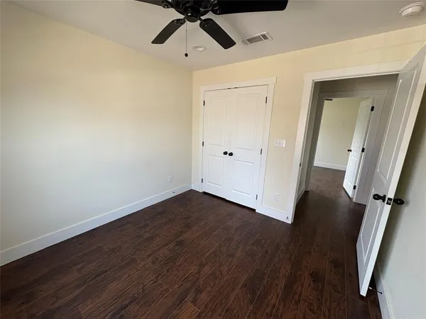 an empty room with wooden floor and ceiling fan