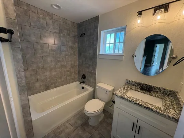 a bathroom with a granite countertop toilet a sink and bathtub