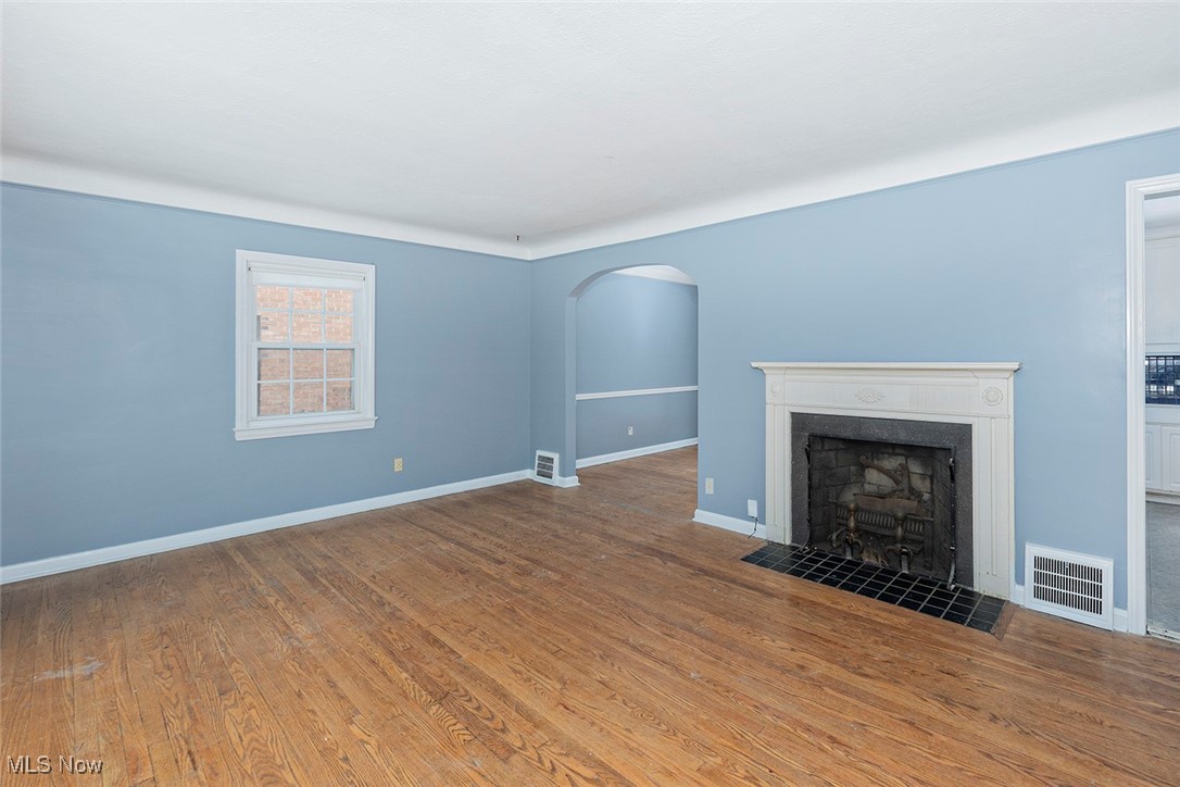 3719 Berkeley Road Cleveland Heights, OH 44118 - Photo 12 of 44 Unfurnished living room with arched walkways, a tile fireplace, and wood finished floors