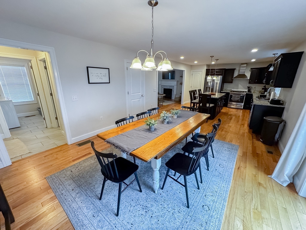 23 Ralph Street Chicopee, MA 01020 - Photo 11 of 42 a dining room with wooden floor a chandelier a wooden table and chairs