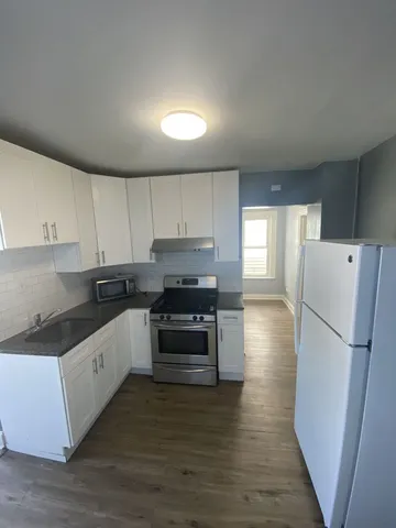 a kitchen with granite countertop a refrigerator and a stove top oven