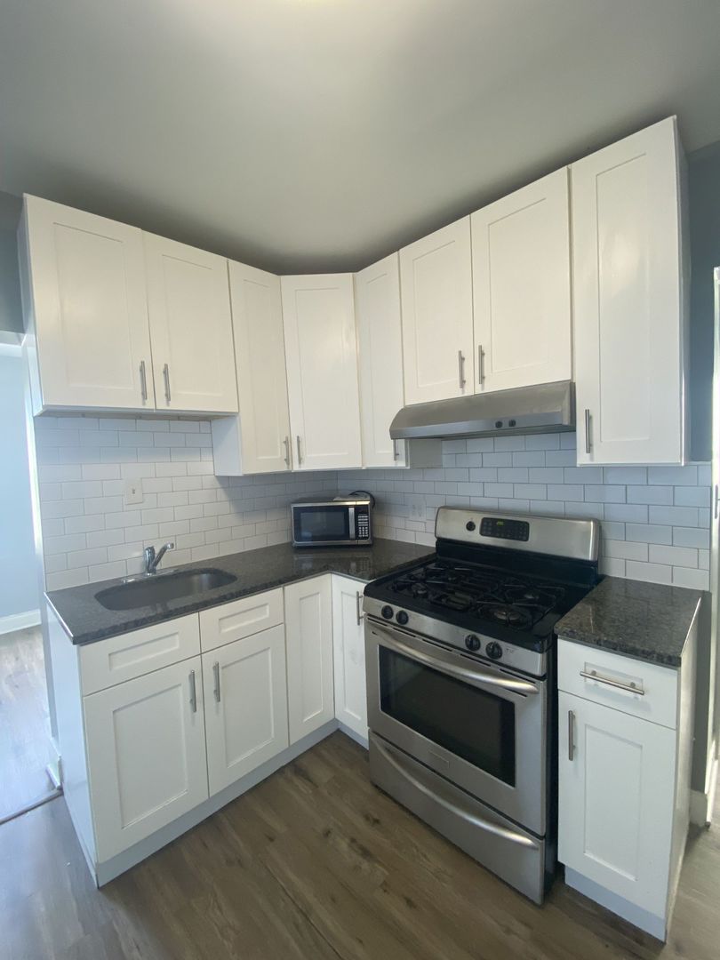 4812 South Elizabeth Street, Unit 2R Chicago, IL 60609 - Photo 5 of 14 a kitchen with granite countertop white cabinets and white appliances