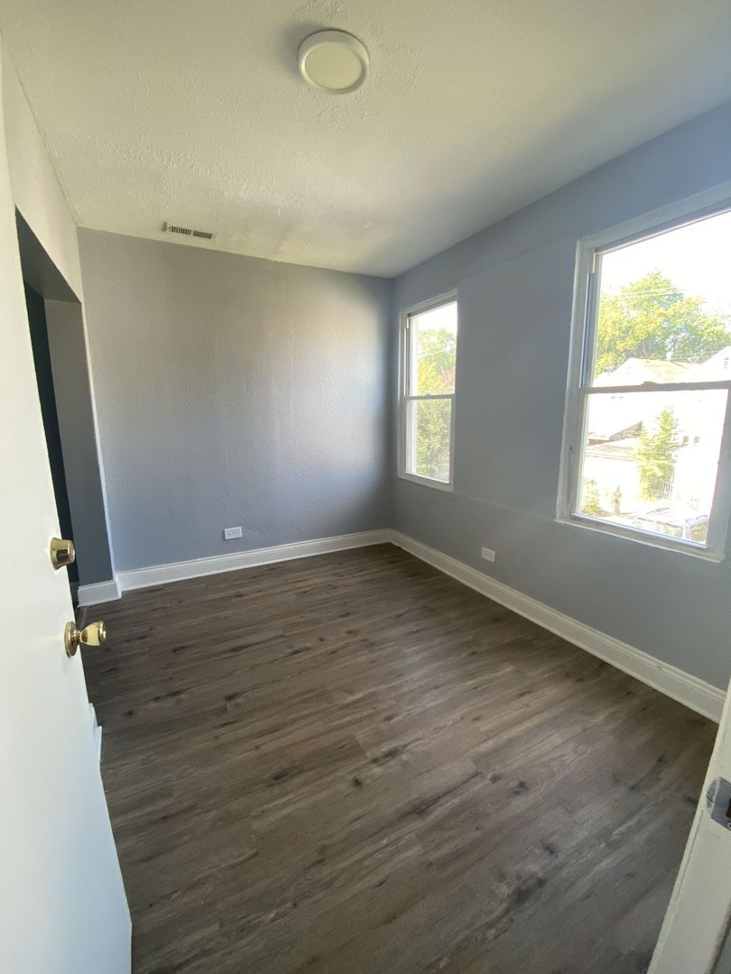 4812 South Elizabeth Street, Unit 2R Chicago, IL 60609 - Photo 7 of 14 an empty room with wooden floor and windows
