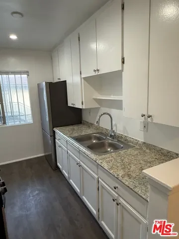a kitchen with granite countertop a sink a stove and cabinets