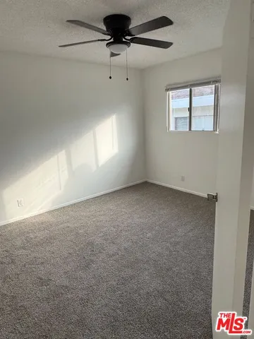 an empty room with windows and fan