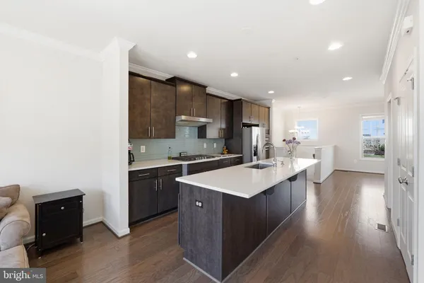 a large kitchen with a large counter top a sink stainless steel appliances and cabinets