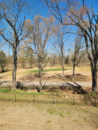 a view of a house with a big yard and large trees