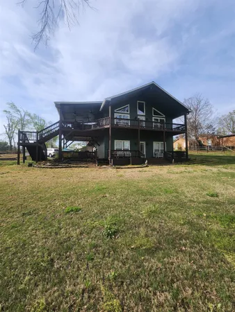 a view of a big house with a big yard and large trees