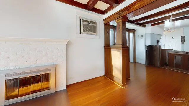 a view of an empty room with kitchen view and a fireplace