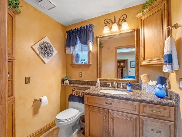 a bathroom with a granite countertop sink and a toilet