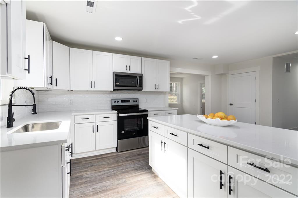 990 Dunlap Roddey Road Rock Hill, SC 29730 - Photo 8 of 28 a kitchen with stainless steel appliances granite countertop a sink stove refrigerator and white cabinets with wooden floor