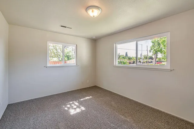 an empty room with windows and ceiling fan