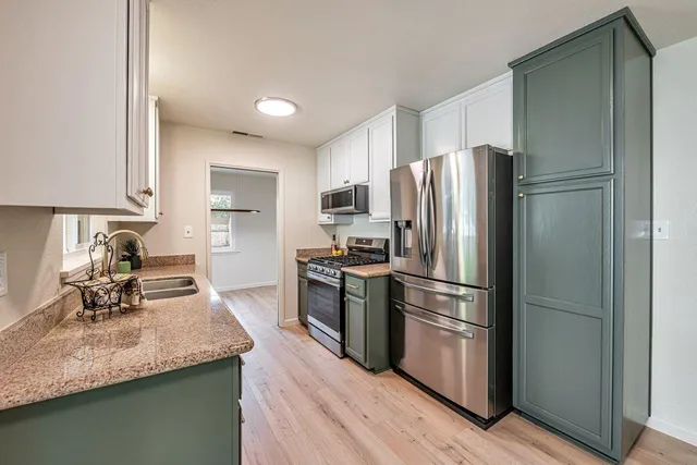a kitchen with stainless steel appliances granite countertop a refrigerator and a sink