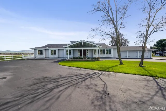 a view of house with a big yard and large trees