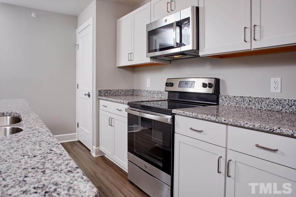 a kitchen with stainless steel appliances granite countertop white cabinets granite counter tops and a hard wood floors