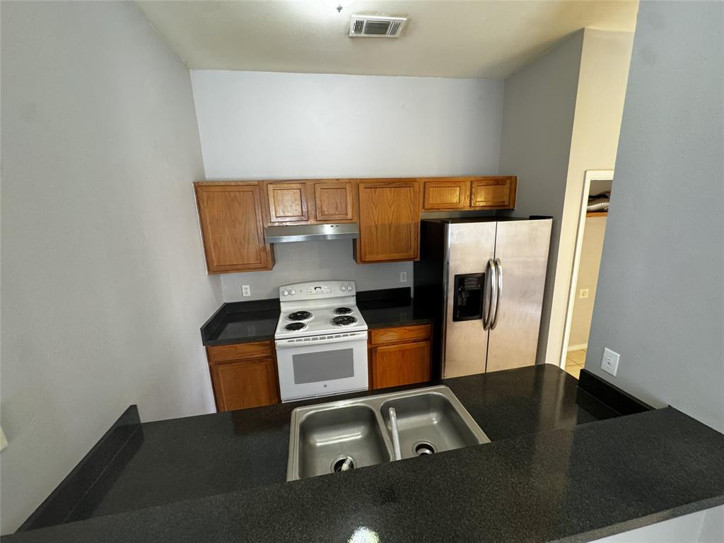 1707 Tina Marie Road, Unit A Arlington, TX 76012 - Photo 20 of 34 Kitchen featuring wood finish cabinetry, white range with electric stovetop, and stainless steel fridge