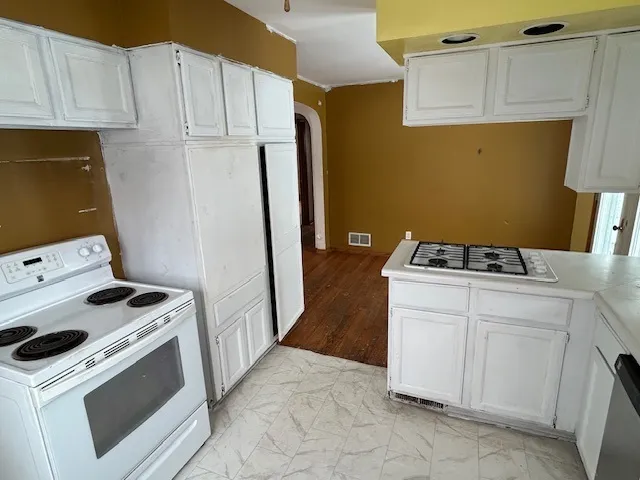 a kitchen with cabinets appliances and wooden floor