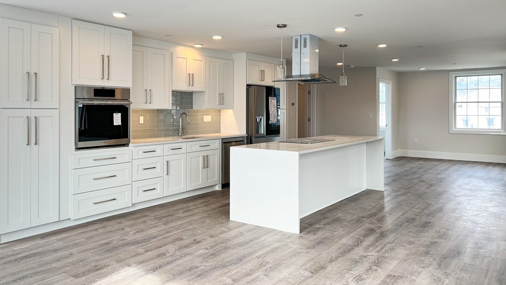 131 Cambridge Street, Unit A Burlington, MA 01803 - Photo 11 of 22 a kitchen with stainless steel appliances kitchen island granite countertop a stove a sink and a refrigerator