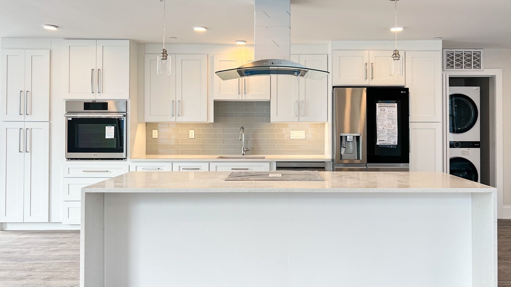 131 Cambridge Street, Unit A Burlington, MA 01803 - Photo 13 of 22 a kitchen with stainless steel appliances granite countertop a refrigerator a oven and white cabinets with wooden floor