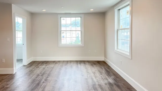 an empty room with wooden floor and windows