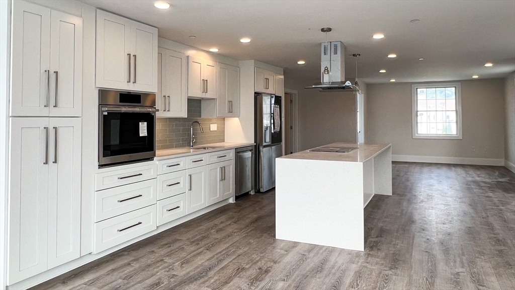 131 Cambridge Street, Unit A Burlington, MA 01803 - Photo 7 of 22 a kitchen with kitchen island white cabinets and refrigerator