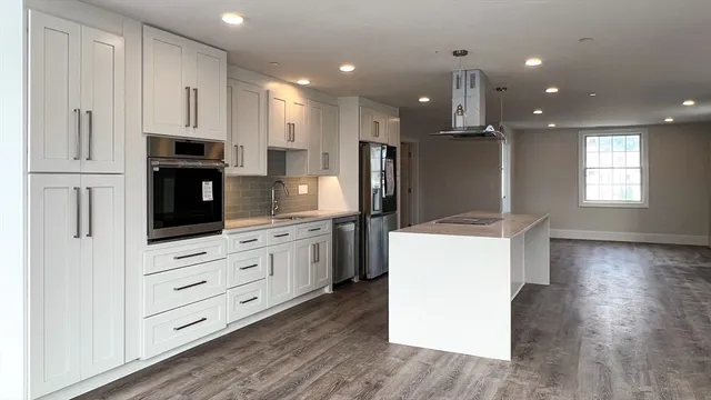 a kitchen with kitchen island wooden cabinets and refrigerator