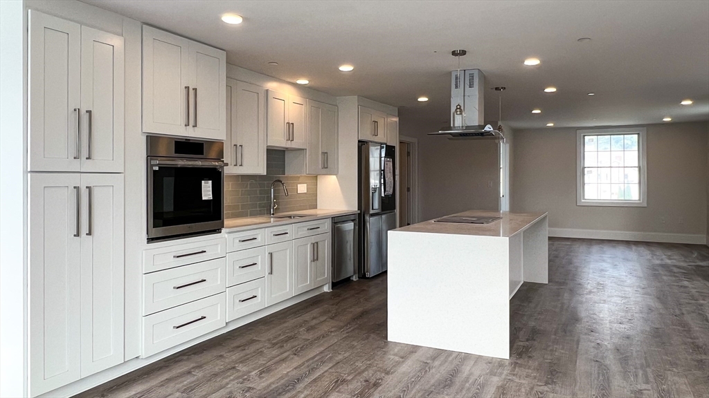 131 Cambridge Street, Unit A Burlington, MA 01803 - Photo 8 of 22 a kitchen with kitchen island wooden cabinets and refrigerator