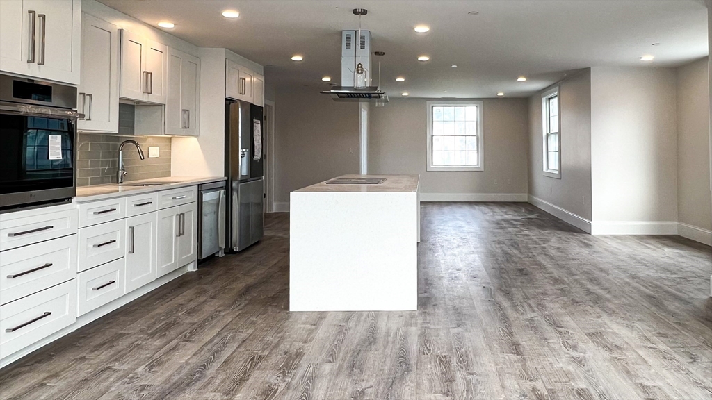 131 Cambridge Street, Unit A Burlington, MA 01803 - Photo 9 of 22 a kitchen with kitchen island white cabinets and stainless steel appliances