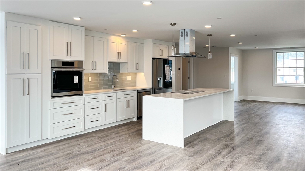 131 Cambridge Street, Unit A Burlington, MA 01803 - Photo 10 of 22 a kitchen with kitchen island white cabinets and stainless steel appliances