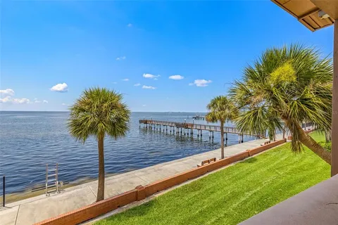 a view of swimming pool with a yard and palm trees