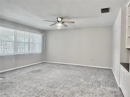 an empty room with windows and fan