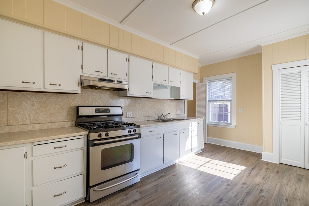 268 Locust Street Fall River, MA 02720 - Photo 12 of 38 a kitchen with stainless steel appliances granite countertop a stove a sink and white cabinets