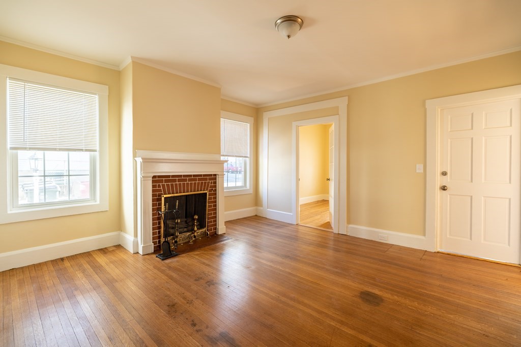 268 Locust Street Fall River, MA 02720 - Photo 9 of 38 an empty room with wooden floor fireplace and windows