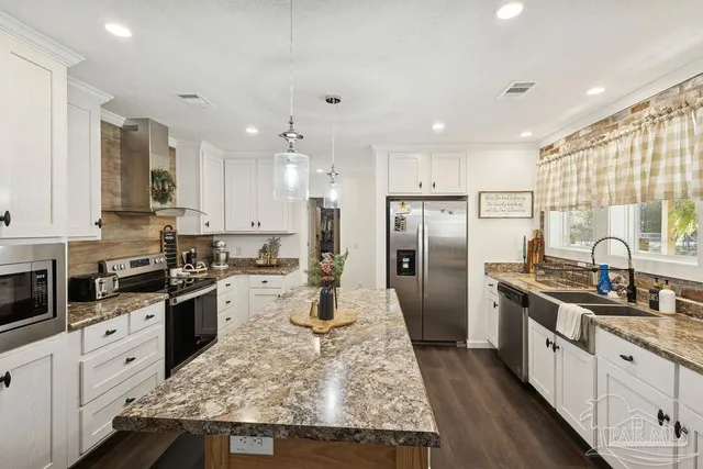 a large kitchen with stainless steel appliances lots of counter space sink refrigerator and cabinets