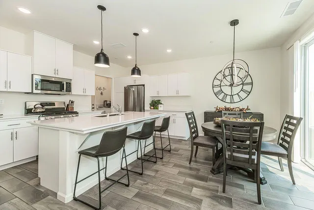 a kitchen with stainless steel appliances a dining table chairs a sink and a chandelier