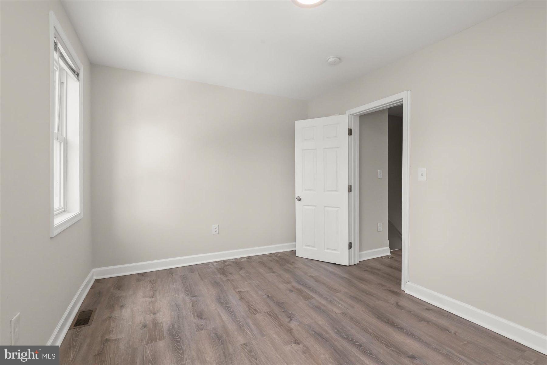 1044 Ellicott Driveway Baltimore, MD 21216 - Photo 12 of 26 a view of an empty room with wooden floor and window