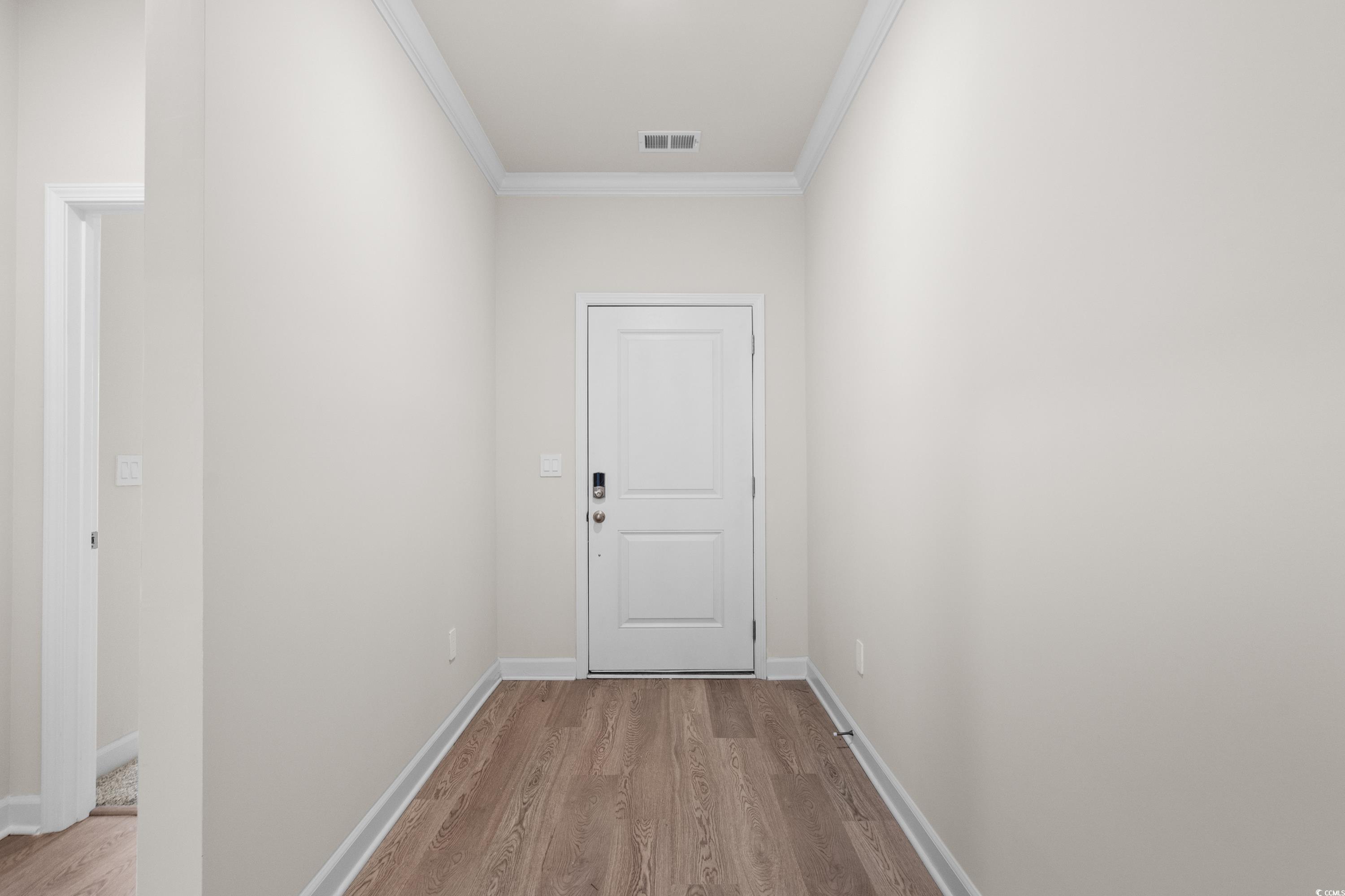 Doorway to outside featuring crown molding and wood finished floors