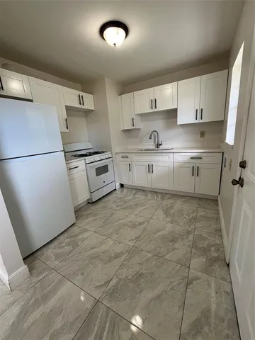 a kitchen with a refrigerator a stove top oven and white cabinets